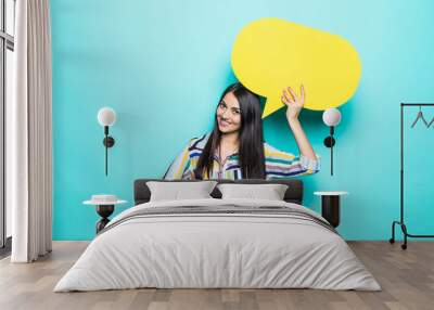 Young woman holding a speech bubble on a blue background Wall mural